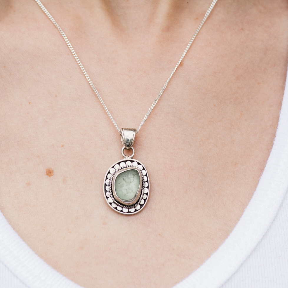 Necklace with a pendant featuring a green gemstone worn by a person.