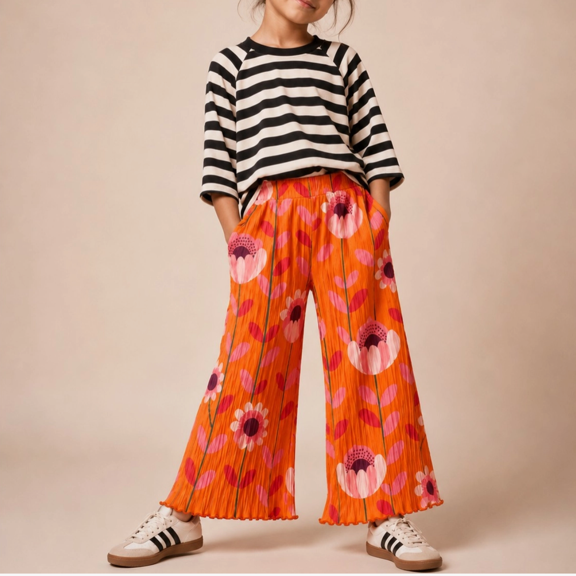 Child wearing a black and white striped shirt with orange floral pants on a beige background