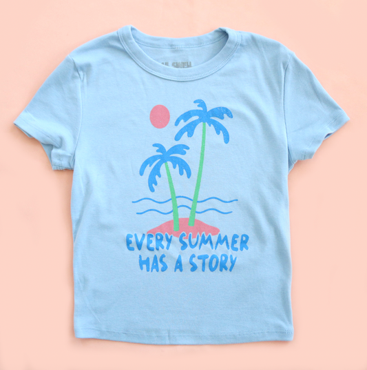 Light blue t-shirt with palm tree design and text on a peach background