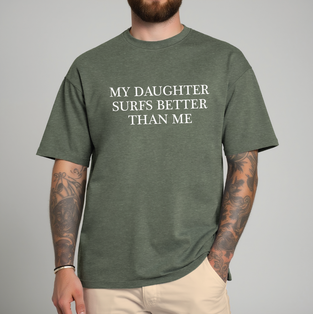 Person wearing a green t-shirt with text 'MY DAUGHTER SURFS BETTER THAN ME' on a gray background