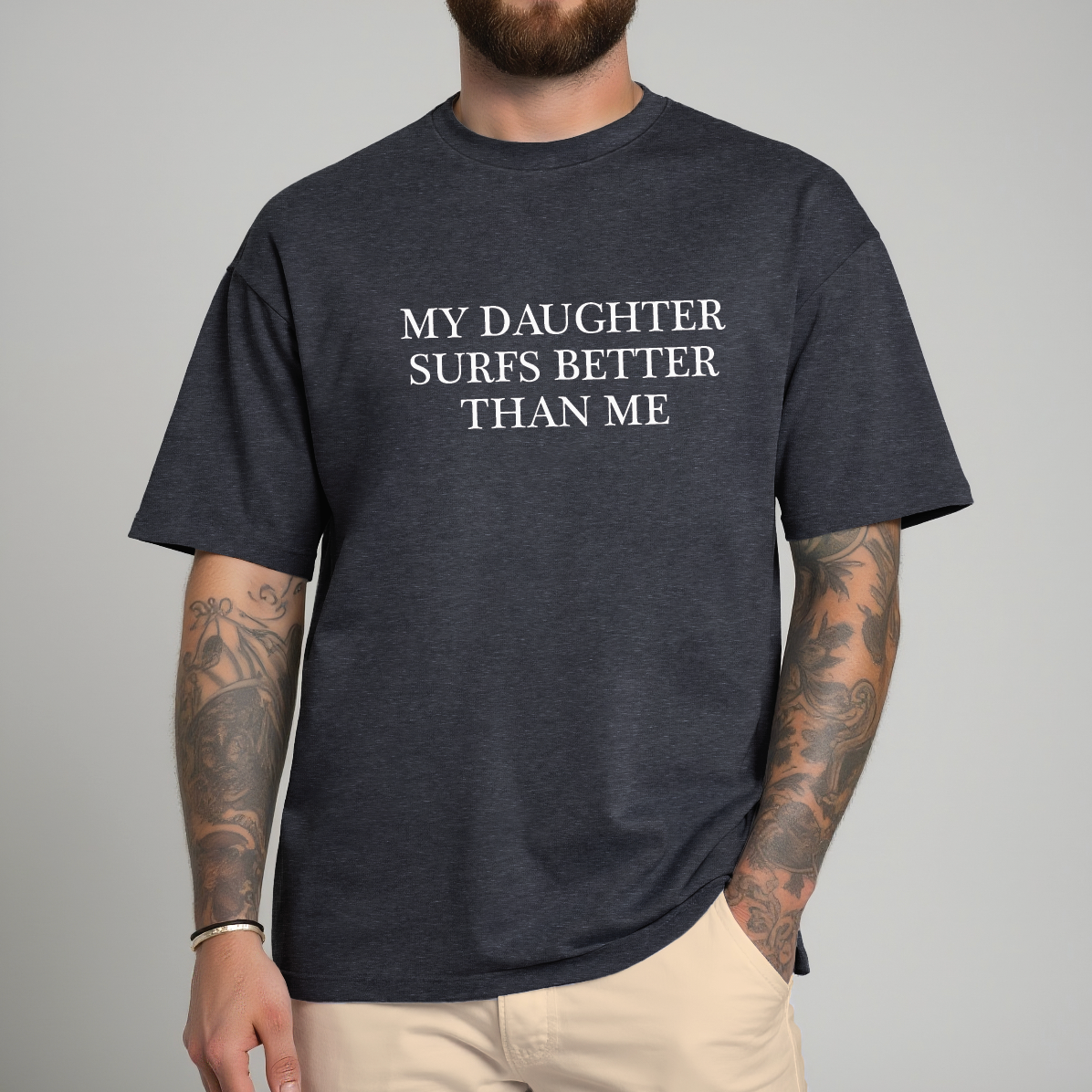 Man wearing a dark gray t-shirt with text 'My daughter surfs better than me' on a gray background